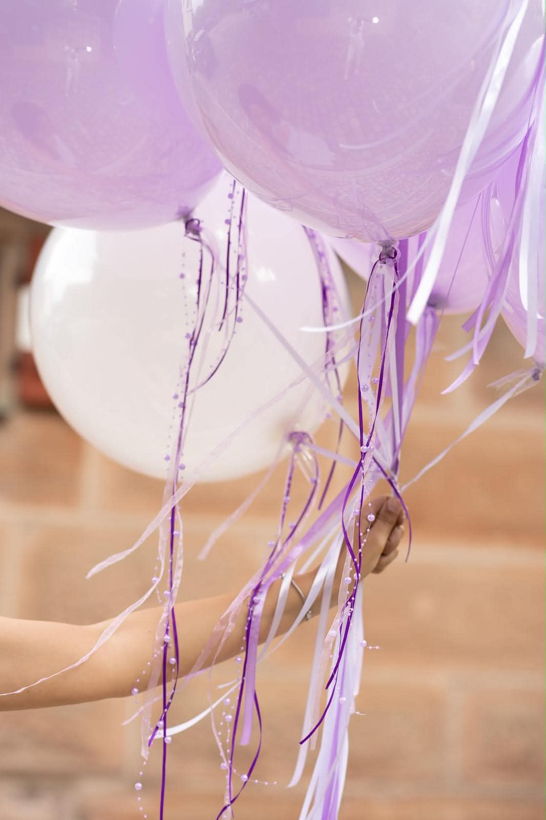 Detail eines Ballon-Bouquets mit lavendelfarbenen Bändern und Perlen